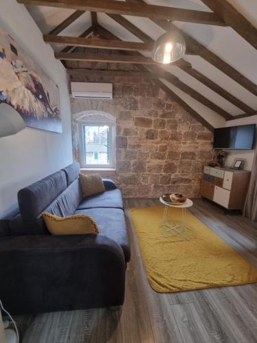 een woonkamer met een blauwe bank en een bakstenen muur bij Heritage Apartments Trumbić in Split