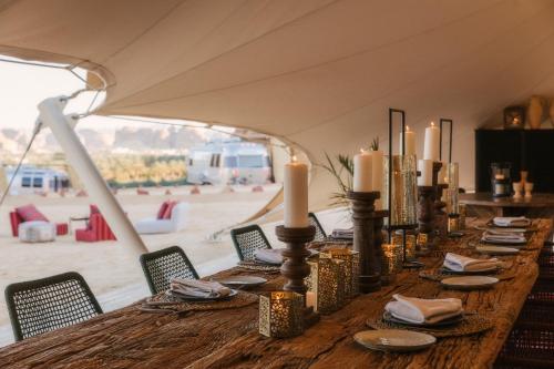a long table in a tent with candles on it at Caravan AlUla by Our Habitas in AlUla