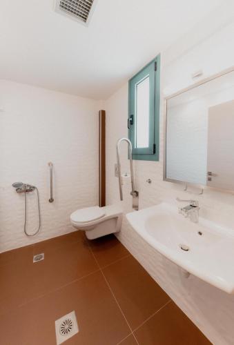 a bathroom with a sink and a toilet and a mirror at Palacio del Sol Luxury Apartments in Nafplio