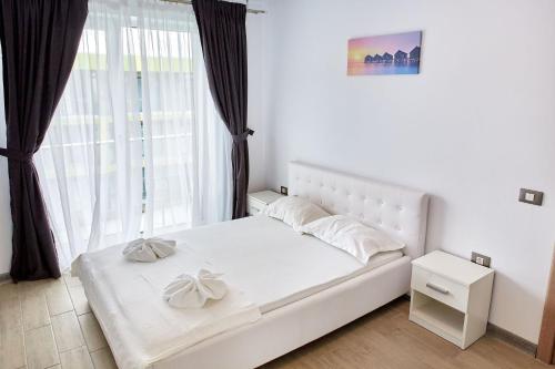 a white bed in a room with a large window at Apartament Iris by Alz in Năvodari