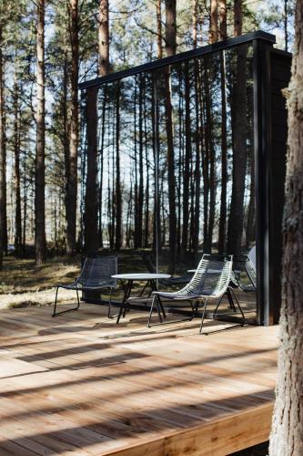 two chairs and a table on a deck with trees at ÖÖD Hötels Laheranna SÄRA -with sauna in Punakivi