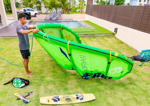 a man is holding a green kayak on the grass at Espetacular Casa de Charme em São Miguel do Gostoso - Salou in São Miguel do Gostoso