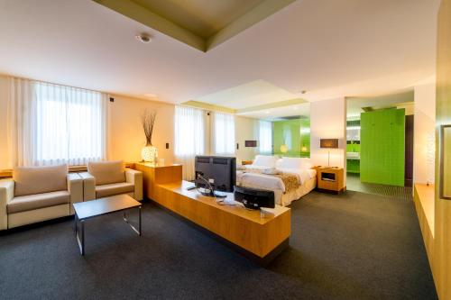 ein Schlafzimmer mit einem Bett, einem TV und einem Sofa in der Unterkunft Hotel-Résidence Am Klouschter in Mondorf-les-Bains