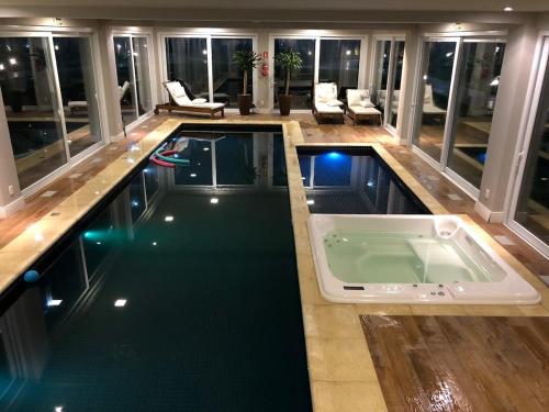 a large swimming pool in a house with a large room at Excelente apartamento em Gramado/RS no Condomínio Casa de Pedra in Gramado