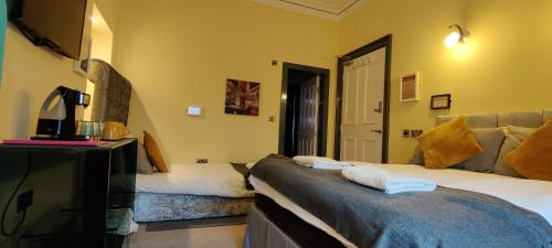 um quarto de hotel com duas camas e uma televisão em Frederick Douglass - Rooms In The City em Edimburgo