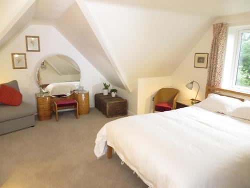een slaapkamer met een wit bed en een spiegel bij The Lawns B & B in Budleigh Salterton