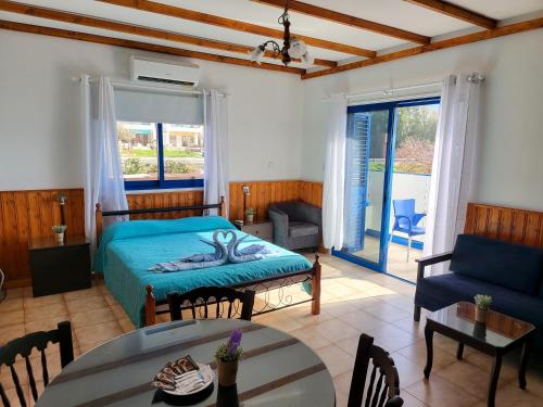 a bedroom with a bed and a living room with a table at Kanalli Apartments in Pomos