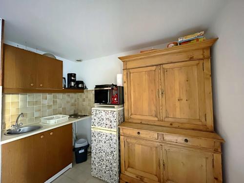 La cuisine est équipée d'une armoire en bois et d'un four micro-ondes. dans l'établissement Ref LS64: Maison 4-6 pers Les Hameaux de Camargue, à Saintes-Maries-de-la-Mer