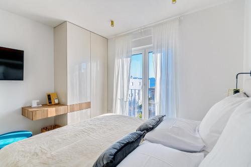 a white bedroom with a bed and a window at Luxury penthouse Marina - Sukošan in Sukošan