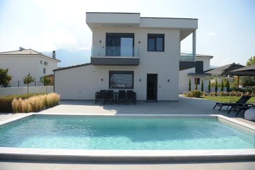 a villa with a swimming pool in front of a house at Luxury Villa Plaka Litochorou with Pool in Plaka Litochorou