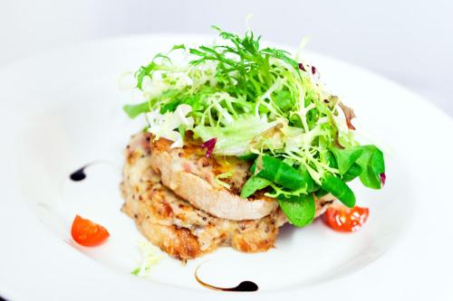 a white plate with a chicken dish with a salad at The Sun Inn in Faversham