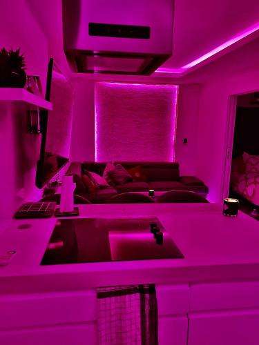 - un salon avec un canapé et des lumières violettes dans l'établissement Sarlat-la-Canada appartement entier magnifique, à Sarlat-la-Canéda