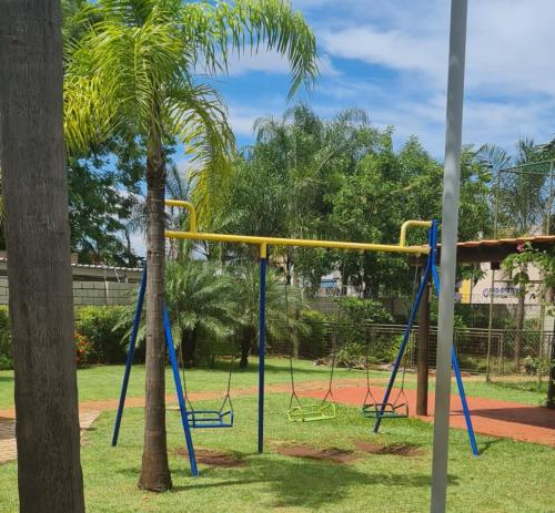 a swing set in a park with a palm tree at Ap confortável prox USP-HC fácil acesso Arena EUROBIKE , estacionamento e wifi 400 mega in Ribeirão Preto