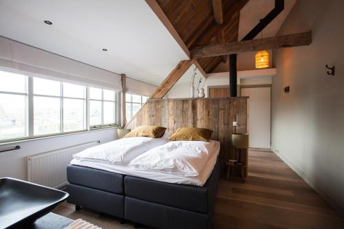 1 dormitorio con 1 cama grande en una habitación con ventanas en BijJoop en Kalenberg