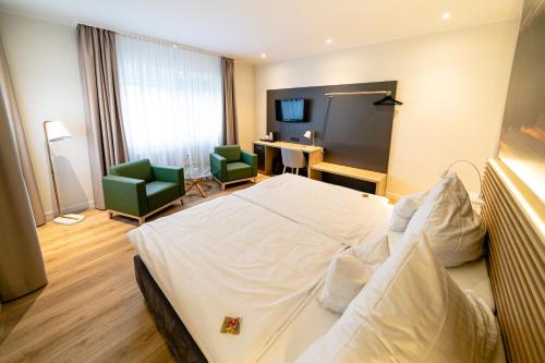 a hotel room with a bed and two green chairs at Hotel Restaurant Kloppendiek in Vreden