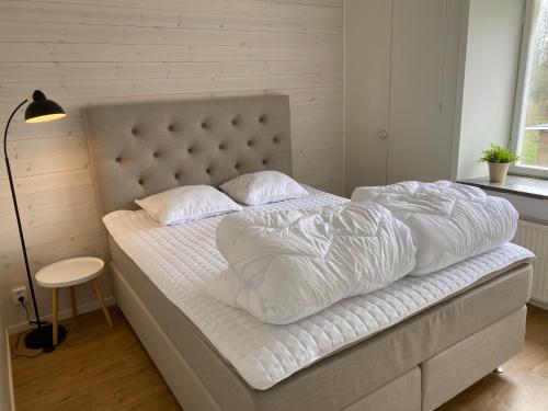 a bed with white sheets and pillows on it at Hangvar Skola Geografisalen in Lärbro