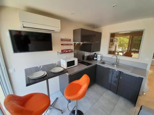 une cuisine avec des chaises orange et un comptoir avec un évier dans l'établissement Appartement Village Naturiste Mojito, au Cap d'Agde