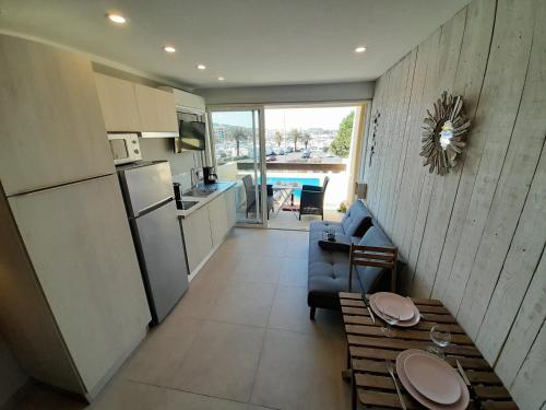 Il dispose d'une cuisine et d'un salon avec un canapé et un réfrigérateur. dans l'établissement Appartement Village Naturiste Cosy, au Cap d'Agde