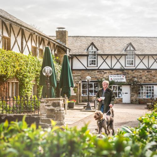 a man walking a dog in front of a building at Last Drop Village Hotel & Spa in Bolton