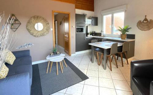 a living room and kitchen with a blue couch and a table at La Maison Blanche in Sangatte