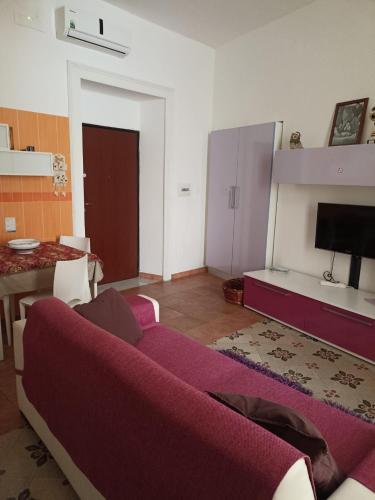 un soggiorno con divano viola e tavolo di Bella Mbriana casa vacanze a Vietri