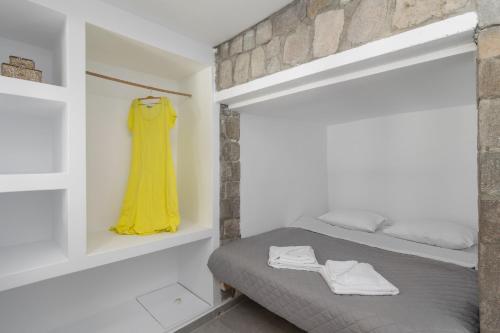 a bedroom with a bed and a yellow dress on a shelf at Almera Sea View Boat House in Adamas