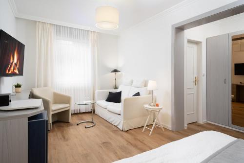 a white living room with a couch and a chair at Hotel Haus am Park in Borkum