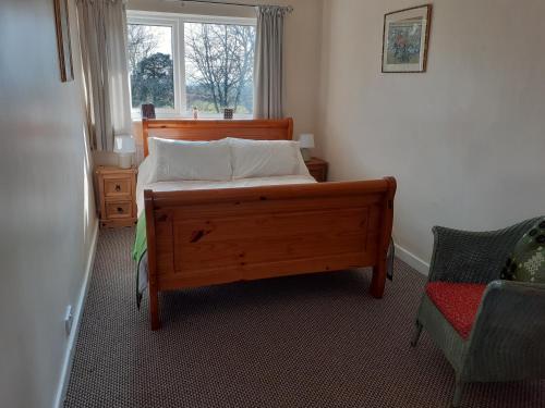 a bedroom with a bed and a window and a chair at Woodpecker Cottage in Carnguwch