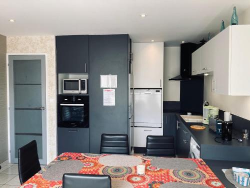 une cuisine avec une table et une cuisine avec des armoires noires dans l'établissement Standing, luminosité à 100m de la mer, T3 prestige, à Saint-Hilaire-de-Riez