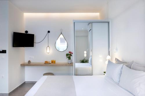 a white bedroom with a bed and a tv at White Swan in Rethymno Town