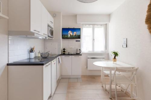une cuisine avec des armoires blanches et une table blanche dans l'établissement Travel Homes - Grand Rue, Petite Venise - Compact & Cosy - Lit mural, à Colmar