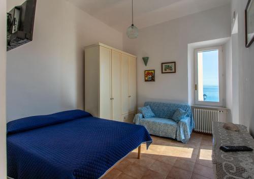a bedroom with a bed and a chair and a window at Casa Alessia in Porto Santo Stefano