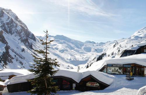 a christmas tree in the snow next to a snow covered mountain at Hôtel des Dromonts by SOWELL COLLECTION in Avoriaz
