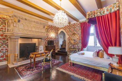 a bedroom with a fireplace and a bed and a chandelier at Chateau Le Prieuré Saumur - La Maison Younan in Chènehutte-les-Tuffeaux