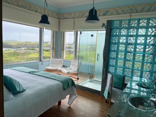 a bedroom with a bed and a glass wall at Villa sobre el mar con acceso a la playa , ideal para familias y grupos in Ribadeo