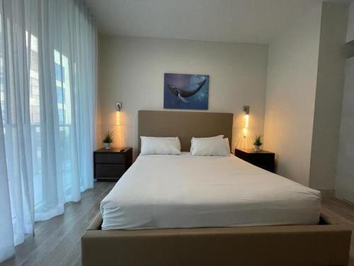 una camera da letto con un grande letto con lenzuola bianche e finestre di COSTA HOLLYWOOD Steps to Beach a Hollywood