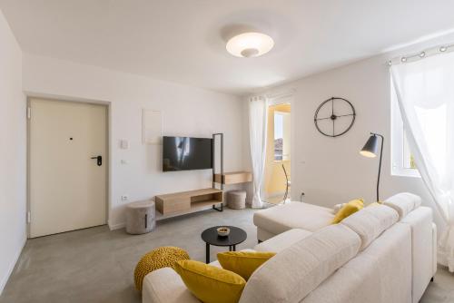 a white living room with a couch and a tv at PORTO SERENO apartments in Šibenik