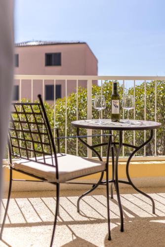 a table and chair with a bottle of wine on a balcony at PORTO SERENO apartments in Šibenik