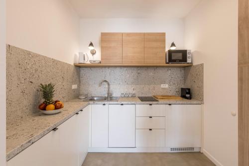 a kitchen with white cabinets and a bowl of fruit at PORTO SERENO apartments in Šibenik
