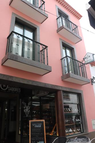 a pink building with two balconies and a store at Residencial Santo António in Santa Cruz