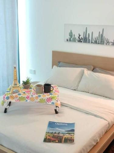 a bed with a book and a tray with the eiffel tower at MUJI STYLE STUDIO Almas 100mbps Pool View Netflix By STAY in Nusajaya