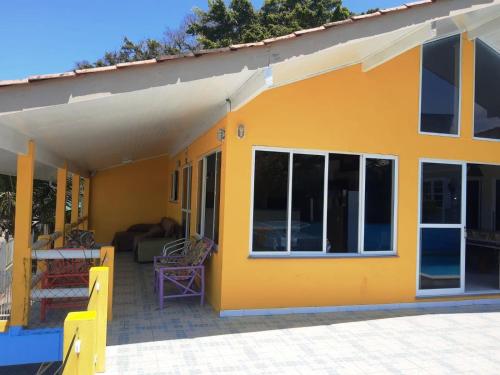 Casa amarilla con puertas de cristal y patio en Mansão Ouro Verde Vlc Frente para o Mar com Piscina, en Piçarras