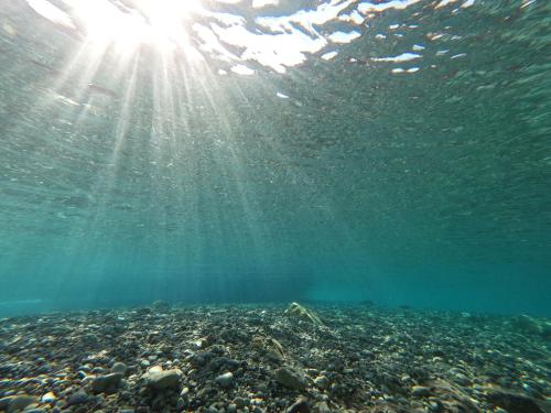 a view of the ocean with the sun shining through the water at Ktima Tzaneti - Coastal Farmhouse in Lakhania