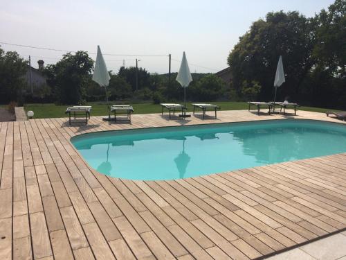 a swimming pool with benches and tables and umbrellas at B&B Sgonico in Sgonico
