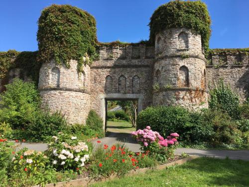 an old stone building with flowers in a garden at Bay Cottage & Bay Stables in Torpoint