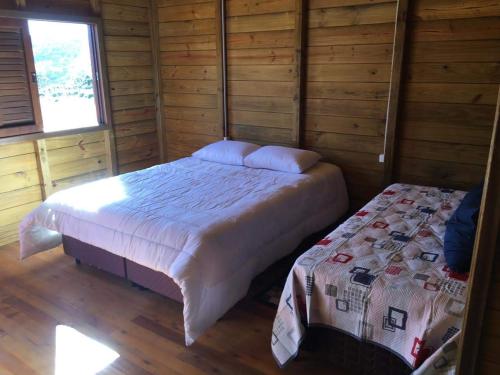 a bedroom with a bed in a wooden cabin at Pousada Bela Tereza in São Joaquim