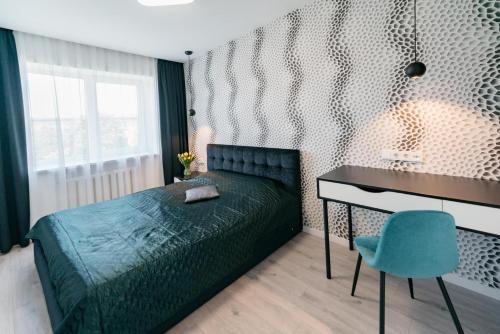 a bedroom with a bed and a desk and a blue chair at Klaipda Gate Apartments in Klaipėda