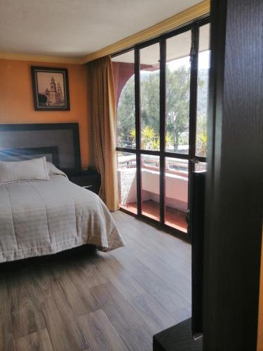 a bedroom with a bed and a large window at Hotel Las Américas in Morelia