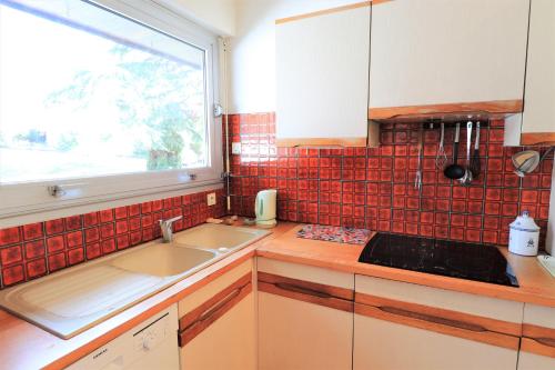 eine Küche mit einem Waschbecken und einem Fenster in der Unterkunft MAISON DU GOLFE in Séné