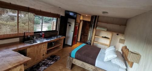 1 dormitorio con 1 cama y lavamanos. en Cabañas Tierra Linda, en Pichilemu